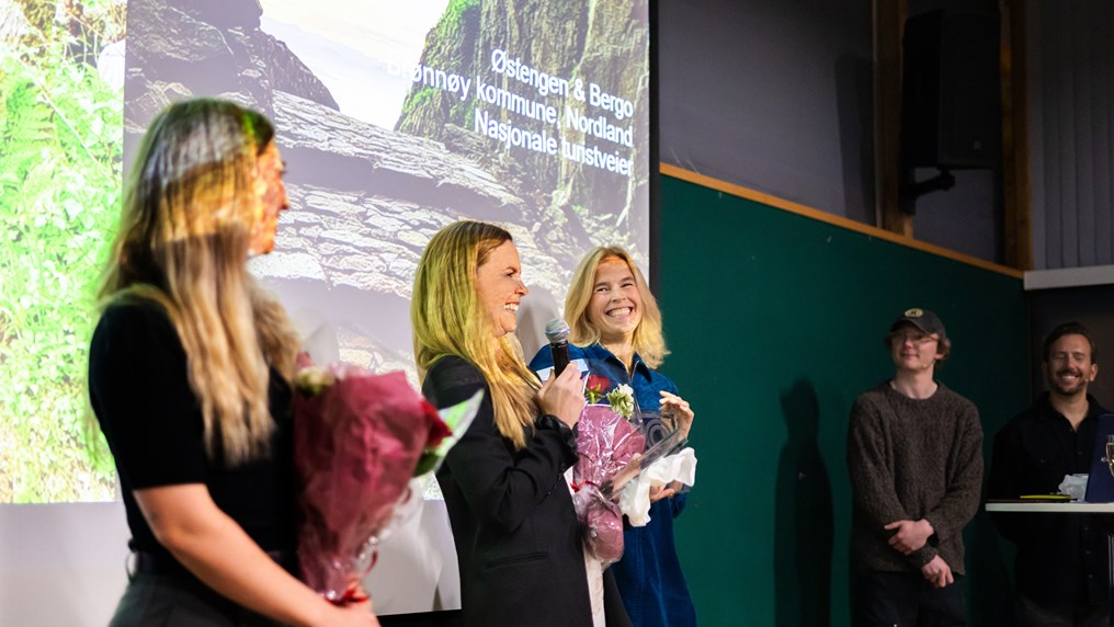 Tre kvinner mottar blomster på en scene.