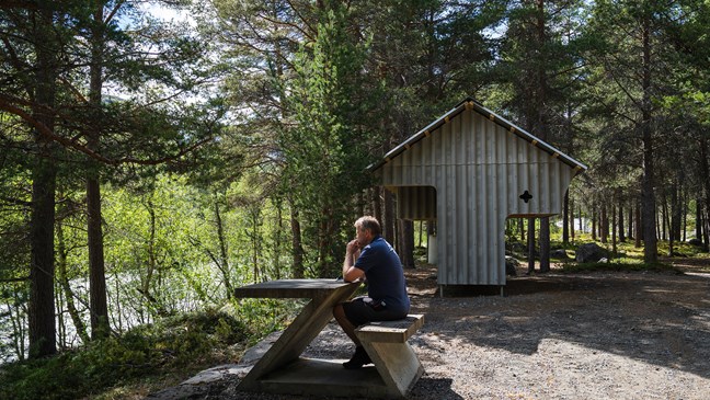 Mann sitter på rastemøbler i skogen.