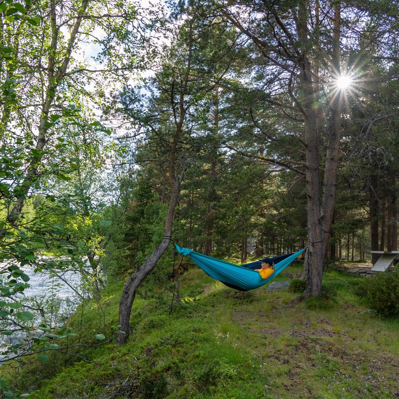 Ung kvinne i hengekøye ved elva.